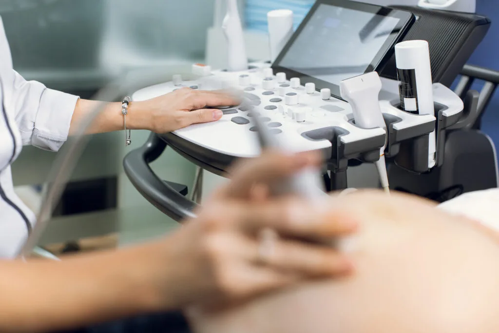 Home 4 Close up cropped image of female doctor obstetrician, pushing buttons on a control panel performing ultrasound sonogram procedure for pregnant woman