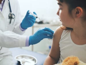 Female doctor giving an injection to a young cute girl.
