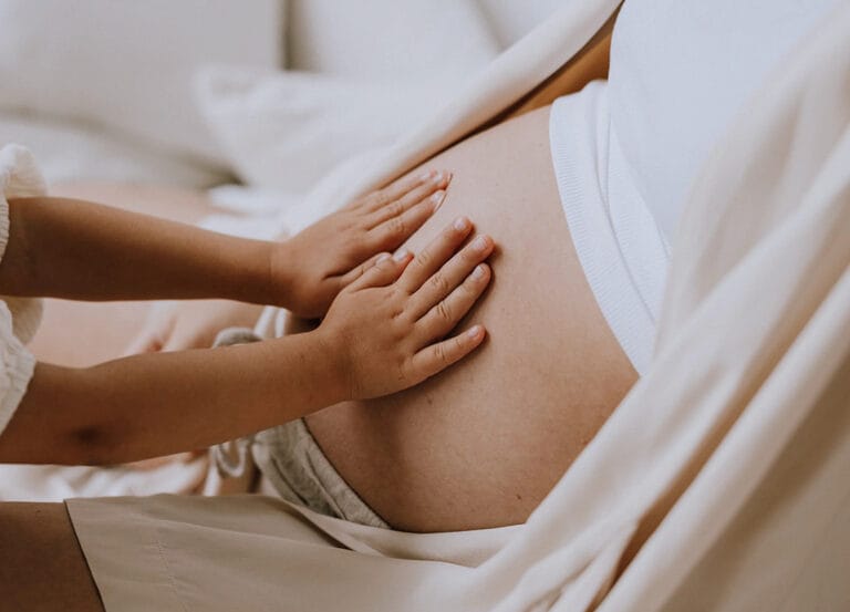 A child touching his mother's pregnant belly during her first trimester.