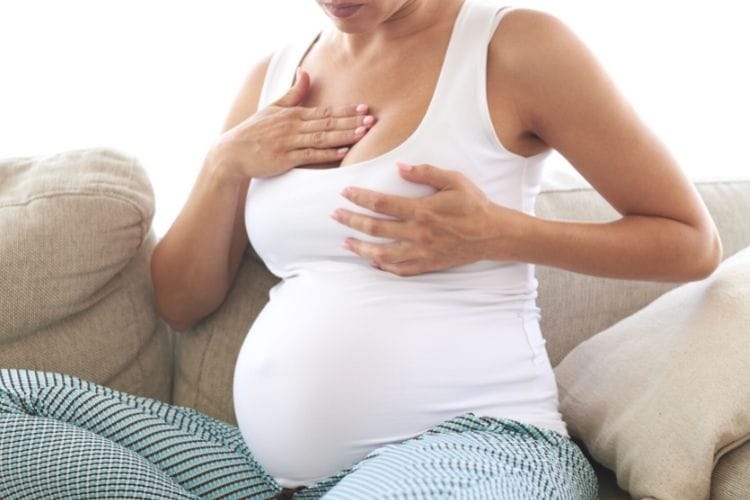 A pregnant woman checking the tenderness of her breast.